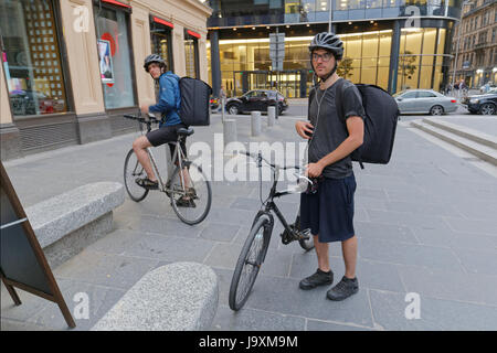 student Twins working for uber Deliveroo Uber delivery bikers cyclists drivers on the street delivering to Glasgow Stock Photo