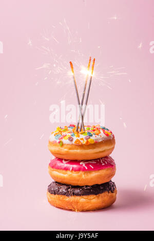 Delicious donuts for birthday on pastel pink background. Stock Photo