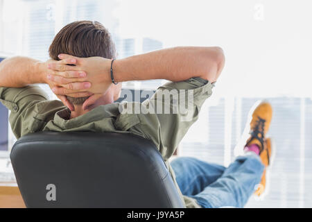 Designer relaxing in a modern office with foot on the desk Stock Photo