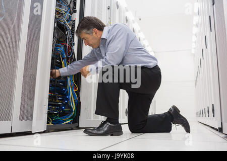 Technician kneeling while repairing the server with his hands in the data center Stock Photo