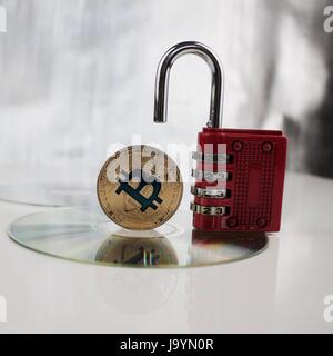 Digital currency physical gold bitcoin near red padlock on the CD Stock Photo