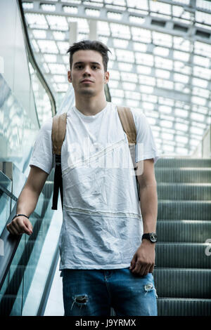 Handsome young man going down escalator, looking straight ahead Stock Photo