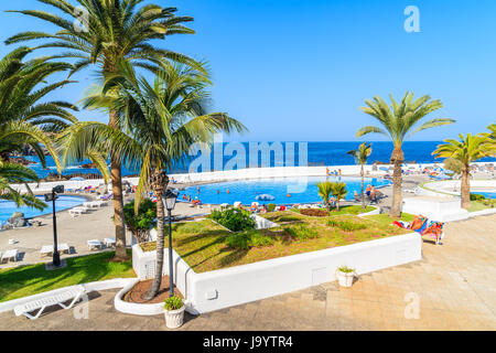 PUERTO DE LA CRUZ, TENERIFE ISLAND - NOV 16, 2015: Palm trees and swimming pools on coastal promenade in Puerto de la Cruz town, Tenerife, Canary Isla Stock Photo