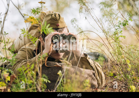 Dyatlovichi, Belarus - October 1, 2016: Young Man Reenactor Dressed As Russian Soviet Red Army Infantry Soldier Of World War II Looking  At An Old Arm Stock Photo