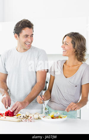 Smiling couple making salad together in the kitchen Stock Photo