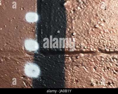 copper spray paint on a wall with black stripe and white dots Stock Photo
