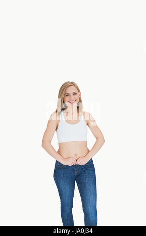 Portrait of slim young woman buttoning jeans over white background Stock Photo