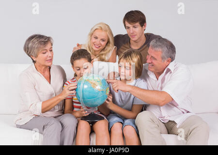 Family looking at globe on couch in sitting room Stock Photo