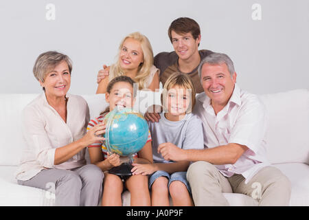 Family portrait looking at camera with a globe in sitting room Stock Photo