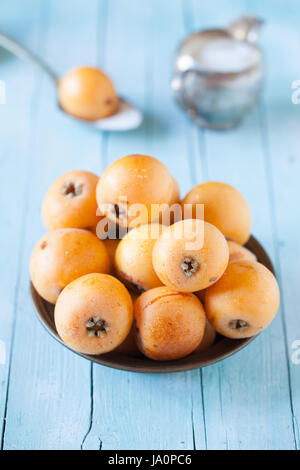 Plate with fresh ripe loquats on wood background. Stock Photo