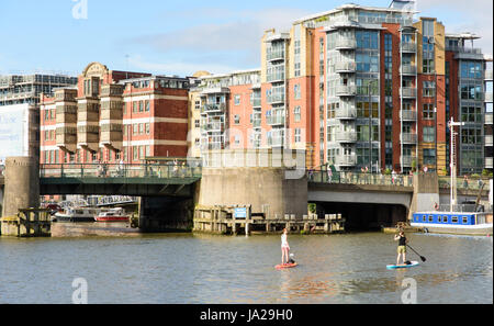 Bristol, England - July 17, 2016: Two women paddleboarding under Redcliffe Bridge on Bristol's Floating Harbour. Stock Photo