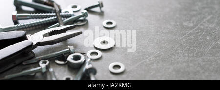 Construction tools. The screws, nuts and bolts with pliers on concrete background. Repair, home improvement concept. Free space for text, top view, flat lay. Banner for website. Stock Photo