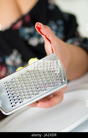 Close up of a woman's hand injured her finger using a grating in plate on kitchen Stock Photo