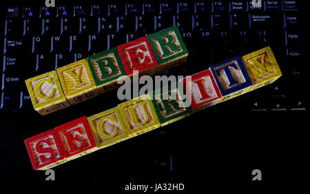 The term cyber security displayed visually on a shadowy dark computer keyboard using colorful wooden blocks Stock Photo
