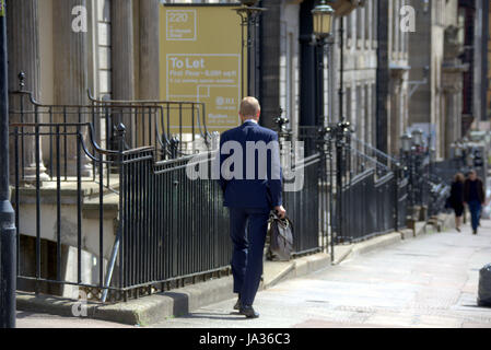 Businessman in suit walking on the street Glasgow Stock Photo