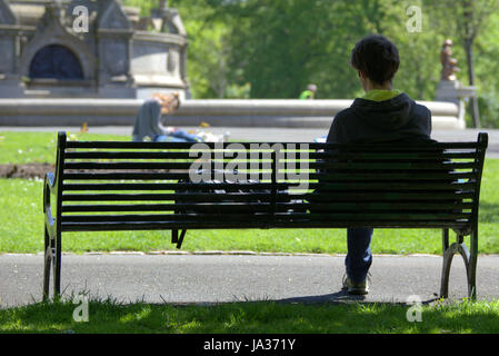 Glasgow Kelvingrove park scenes boy sitting bench eyeing girl Stock Photo