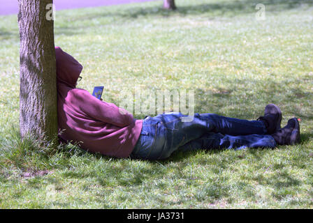 Glasgow Kelvingrove park scenes hoody texting teenager alone Stock Photo