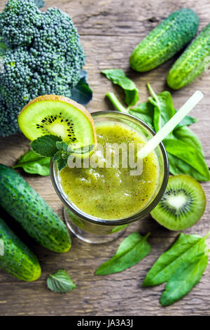 Green vegetable and herbs smoothie with heart of poppy and sesame seeds over rustic wooden background Stock Photo