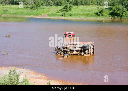 the broken truck lies in dirty water Stock Photo