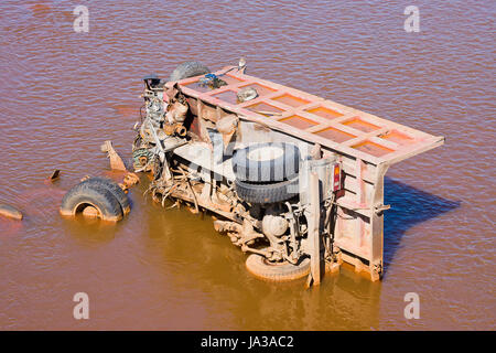 the broken truck lies in dirty water Stock Photo