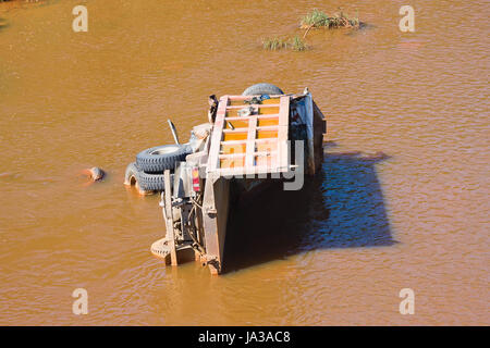 the broken truck lies in dirty water Stock Photo