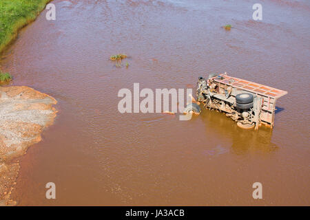 the broken truck lies in dirty water Stock Photo