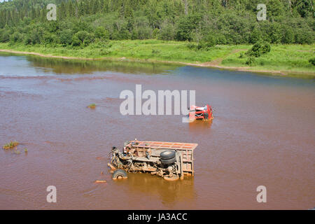 the broken truck lies in dirty water Stock Photo