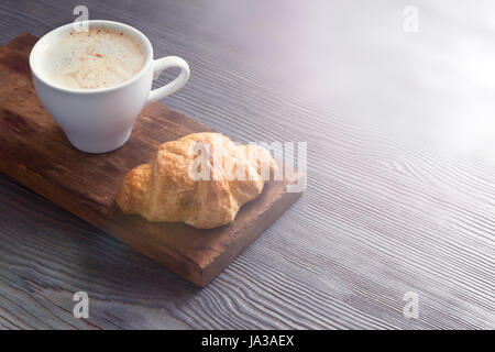 Coffee with croissant for breakfast. French croissant and Cappuccino coffee, tint image with copy space. Stock Photo