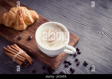 Coffee with croissant for breakfast. Cappuccino coffee and french croissant, tint image. Stock Photo