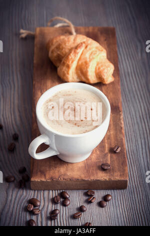 Coffee with croissant for breakfast. Cappuccino coffee and french croissant, tint image. Stock Photo