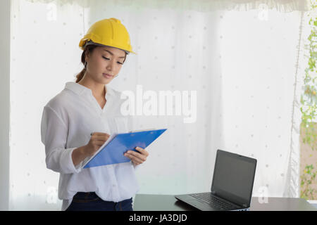 Asian women engineering inspecting and working and holding blueprints at office Stock Photo