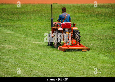 a man on mower cutting grass in football field Stock Photo