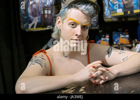 Posed portrait of a transitioning transgender woman with orange eyebrows blue hair and red nail polish. In Manhattan, New York City. Stock Photo