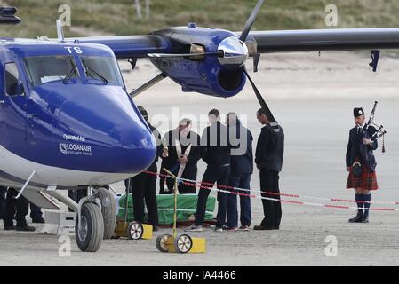 Fr.John Paul MacKinnon blesses the coffin of Eilidh MacLeod draped in the Barra flag at Traigh Mhor beach at Barra airport after it arrived by chartered plane. The body of the Manchester bomb victim was flown home to the devastated community on the island of Barra ahead of her funeral. Stock Photo