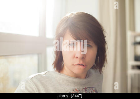 Caucasian woman in turmoil biting lips and frowns Stock Photo