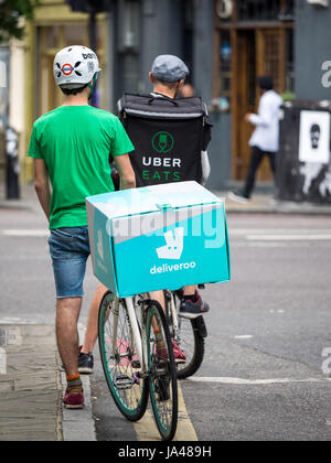 Deliveroo and Uber Eats delivery riders chat while waiting for orders