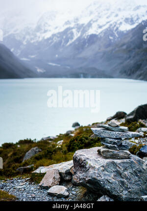 Rocks piled in a cairn in front of hooker lake in New Zealand. Tranquil scene with mountains in the background. Stock Photo