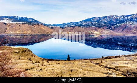 Kamloops Lake in BC, Canada, which is a wide portion of the Thompson River, on a cold winter day with the surrounding mountain reflecting in the water Stock Photo