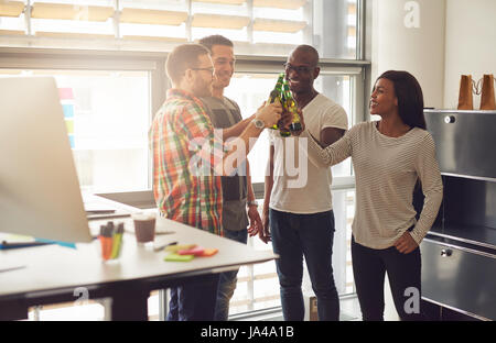 Smiling young group of office workers resting with the beer in the office. Stock Photo