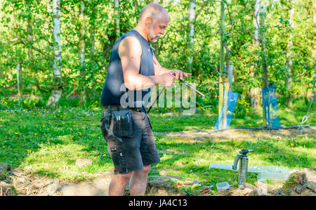 Simrishamn, Sweden - May 19, 2017: Environmental documentary. Electrician working with mending electrical signal cables accidentally torn of by excava Stock Photo