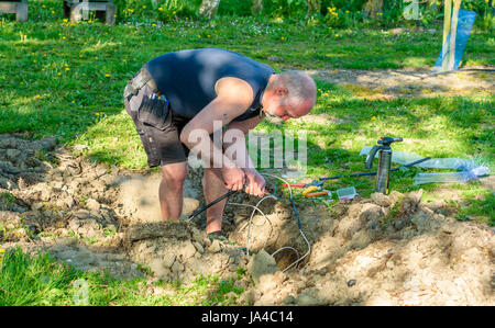 Simrishamn, Sweden - May 19, 2017: Environmental documentary. Electrician working with mending electrical signal cables accidentally torn of by excava Stock Photo