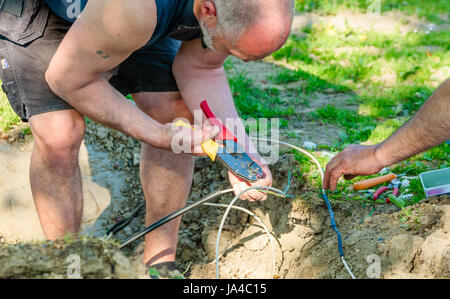 Simrishamn, Sweden - May 19, 2017: Environmental documentary. Electrician working with mending electrical signal cables accidentally torn of by excava Stock Photo