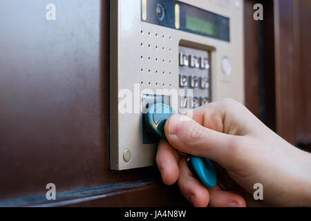 The girl opens the front door with a magnetic tablet. Doorphone as a means of security against robbery. Stock Photo