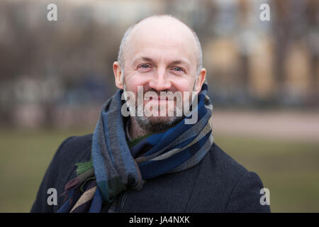 A middle-aged man in a scarf and jacket for a walk around the city. Stock Photo