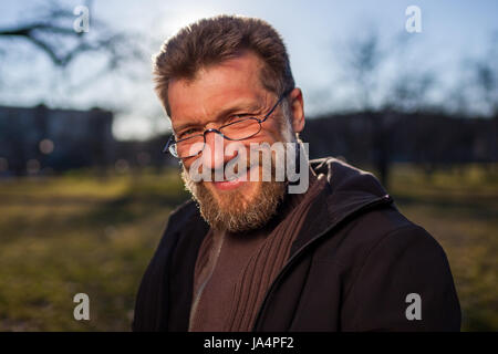 Portrait of a mature man in glasses on a background of nature. Stock Photo
