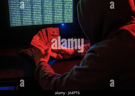 Cyber criminal calculates revenue from extortion or a virus program. Stock Photo