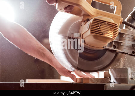The joiner saws a piece of wood in parts on with electric tool Stock Photo