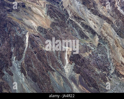 The huge vertical wall of the sedimentary rock is a different cove: burgundy, gray, white, purple, natural art, Himalayas. Stock Photo