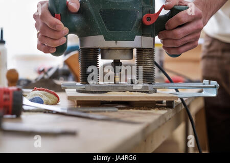 The carpenter makes holes with a drill in a wooden part Stock Photo