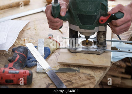 The carpenter makes holes with a drill in a wooden part Stock Photo